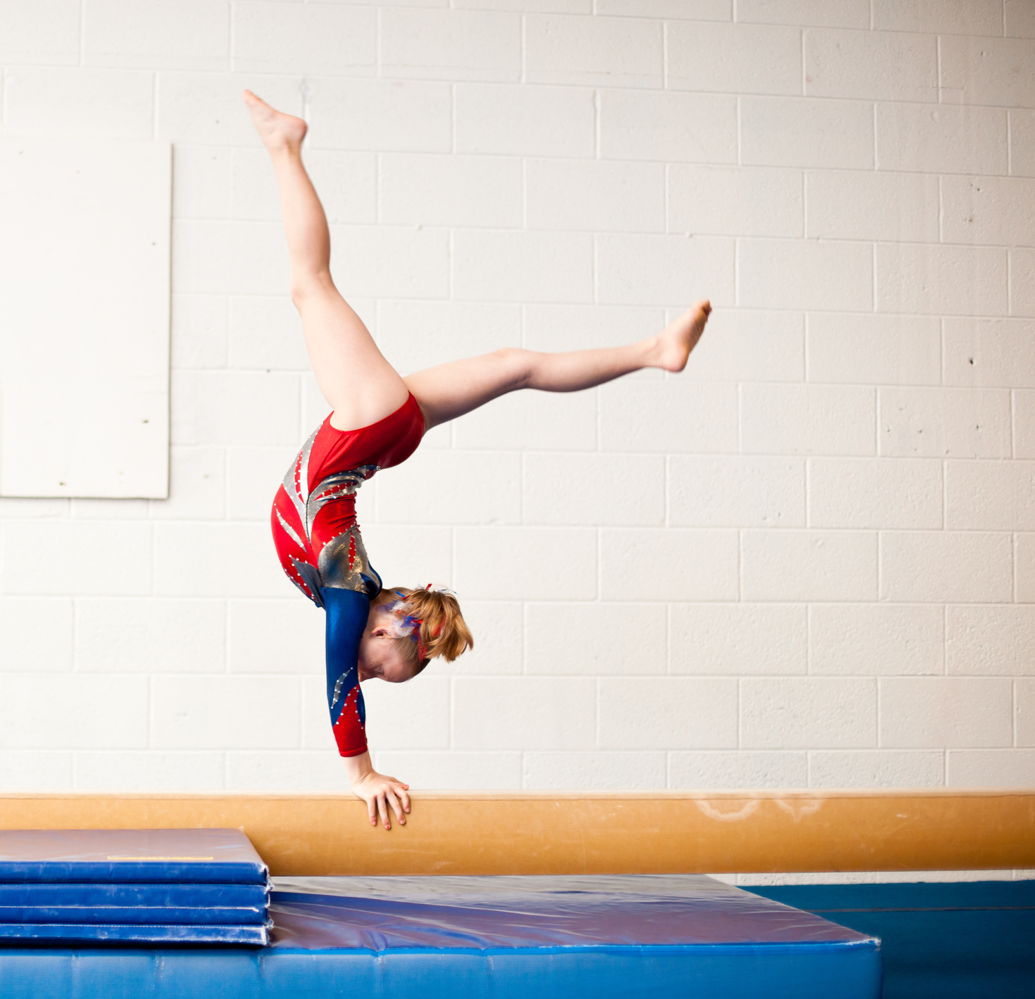 Young Gymnast Performing Walkover on Balance Beam